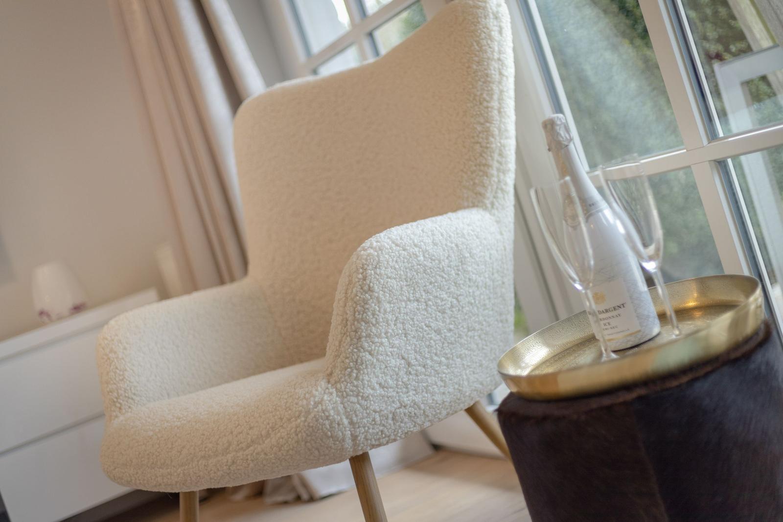 A cream-colored seating area beside a window with a tray holding champagne and glasses.