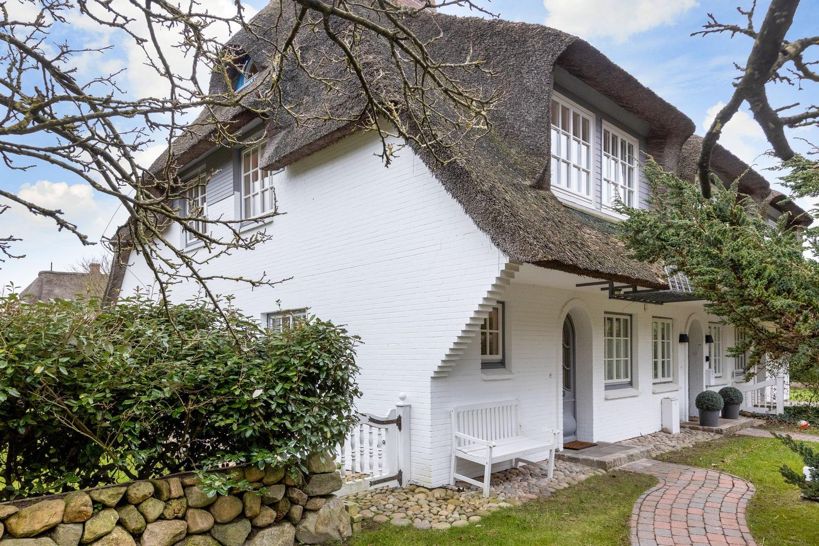 White walls with thatched roof, white bench, and paved terrace.