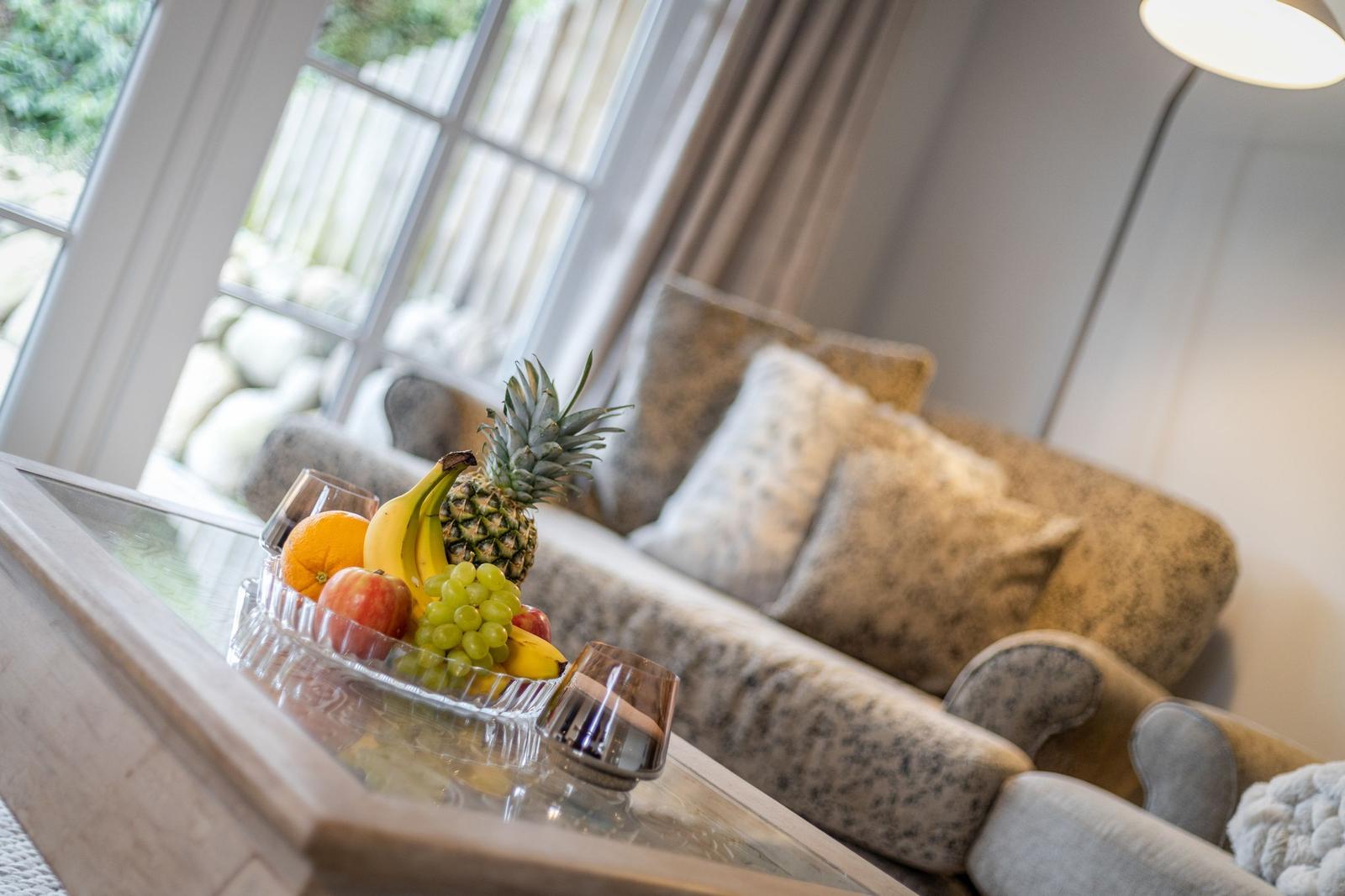 Living room with sofa, fruit bowl, and window view.