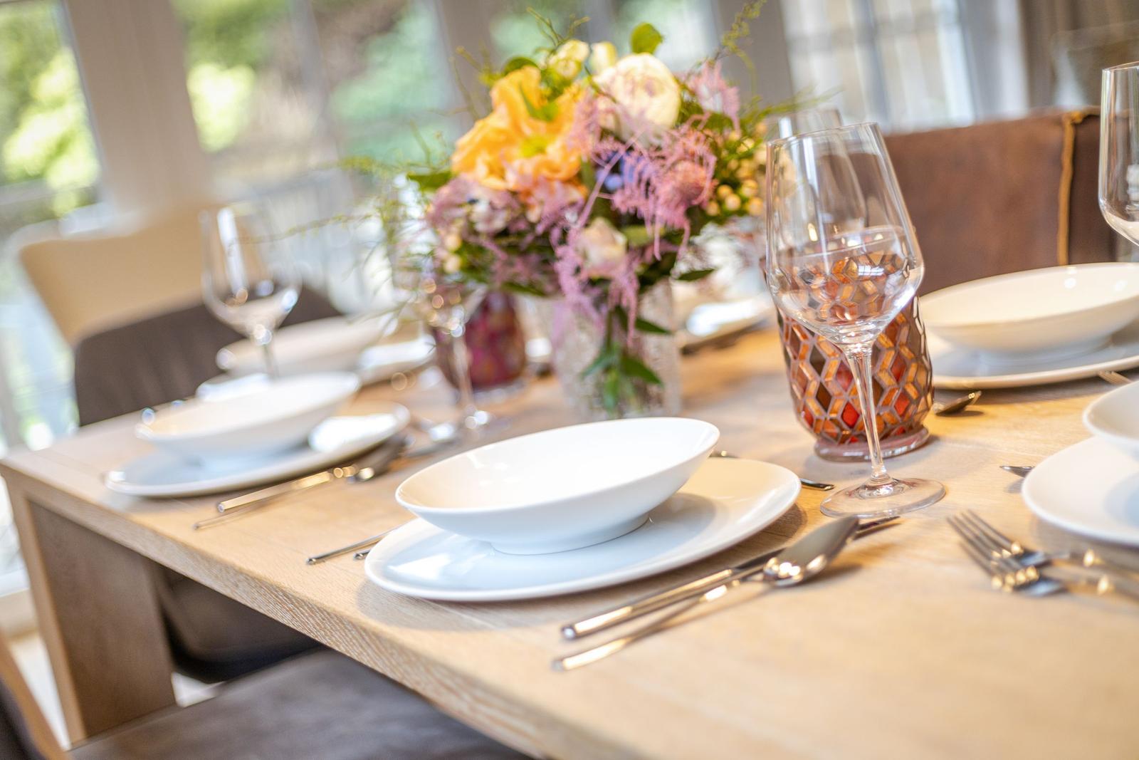 Table with white plates, glasses, and flower arrangement.