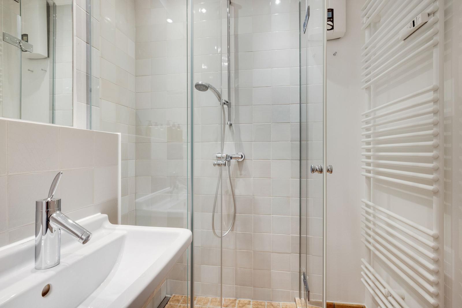 Badezimmer mit Dusche, Waschbecken und Heizkörper