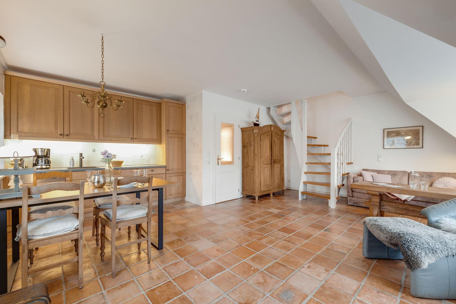 Küche mit Esstisch, Wohnbereich mit Sofa und Holztreppe zur Galerie.