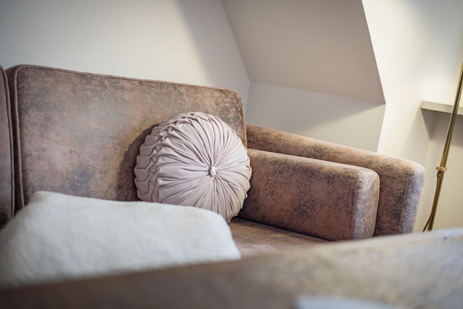 Ein Sofa mit Kissen in einem Raum mit schrägen Wänden.