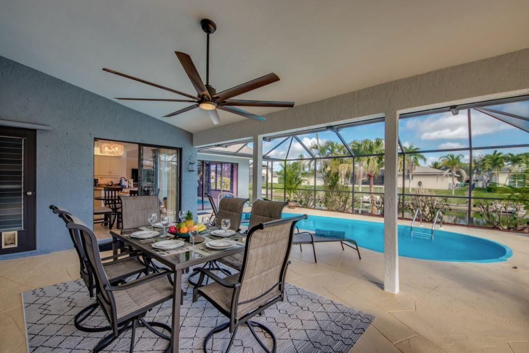 Terrasse mit Esstisch, Pool und Sicht auf Palmen