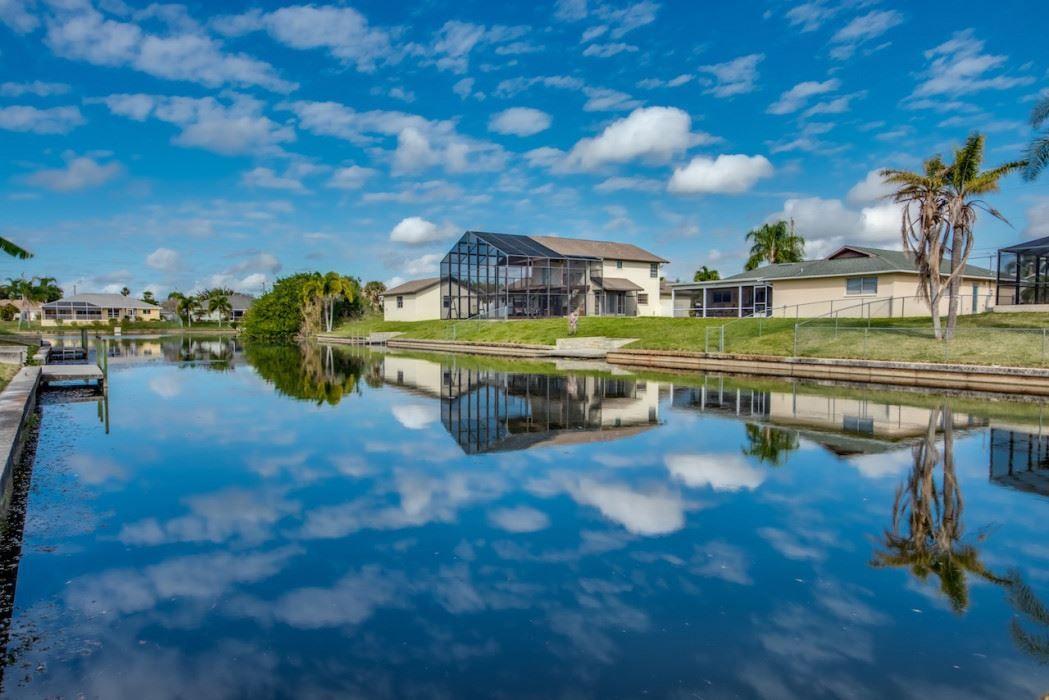 Haus am Wasser mit Reflexion im See und Palmen im Hintergrund.