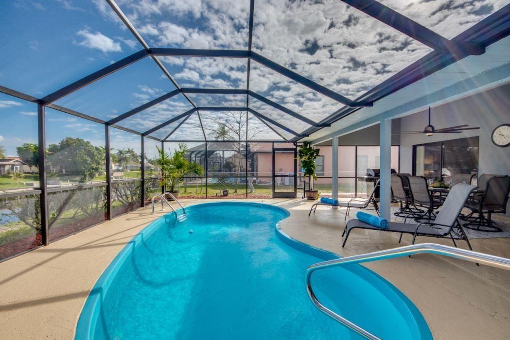 Poolbereich unter Glasdach mit Liegestühlen und Blick auf Garten.