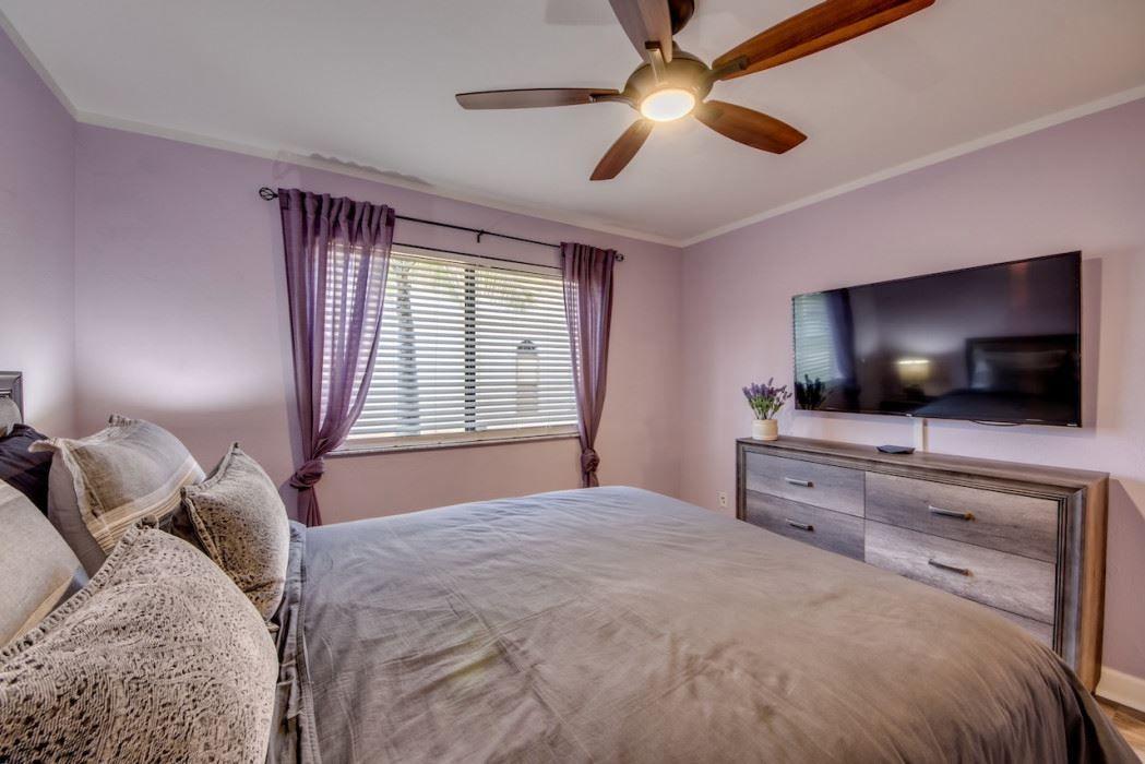 Schlafzimmer mit Bett, TV und Fenster mit Jalousien.