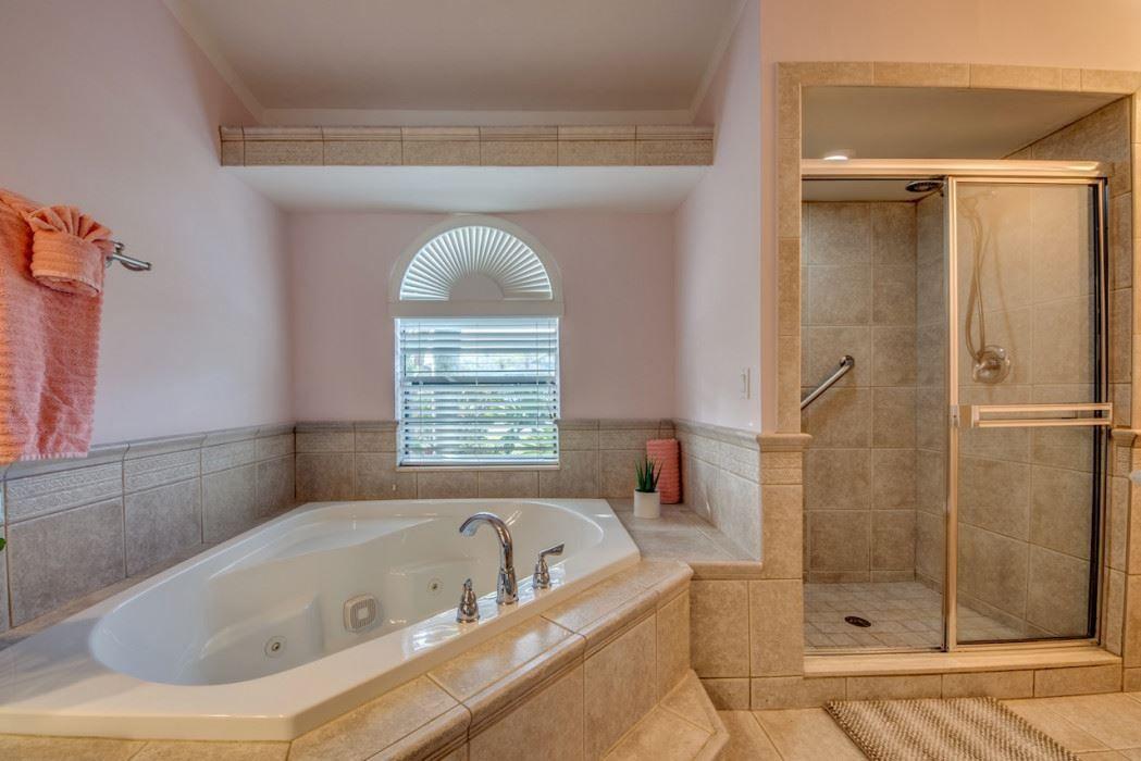 Badezimmer mit Whirlpool, Dusche und Fenster mit Jalousie.