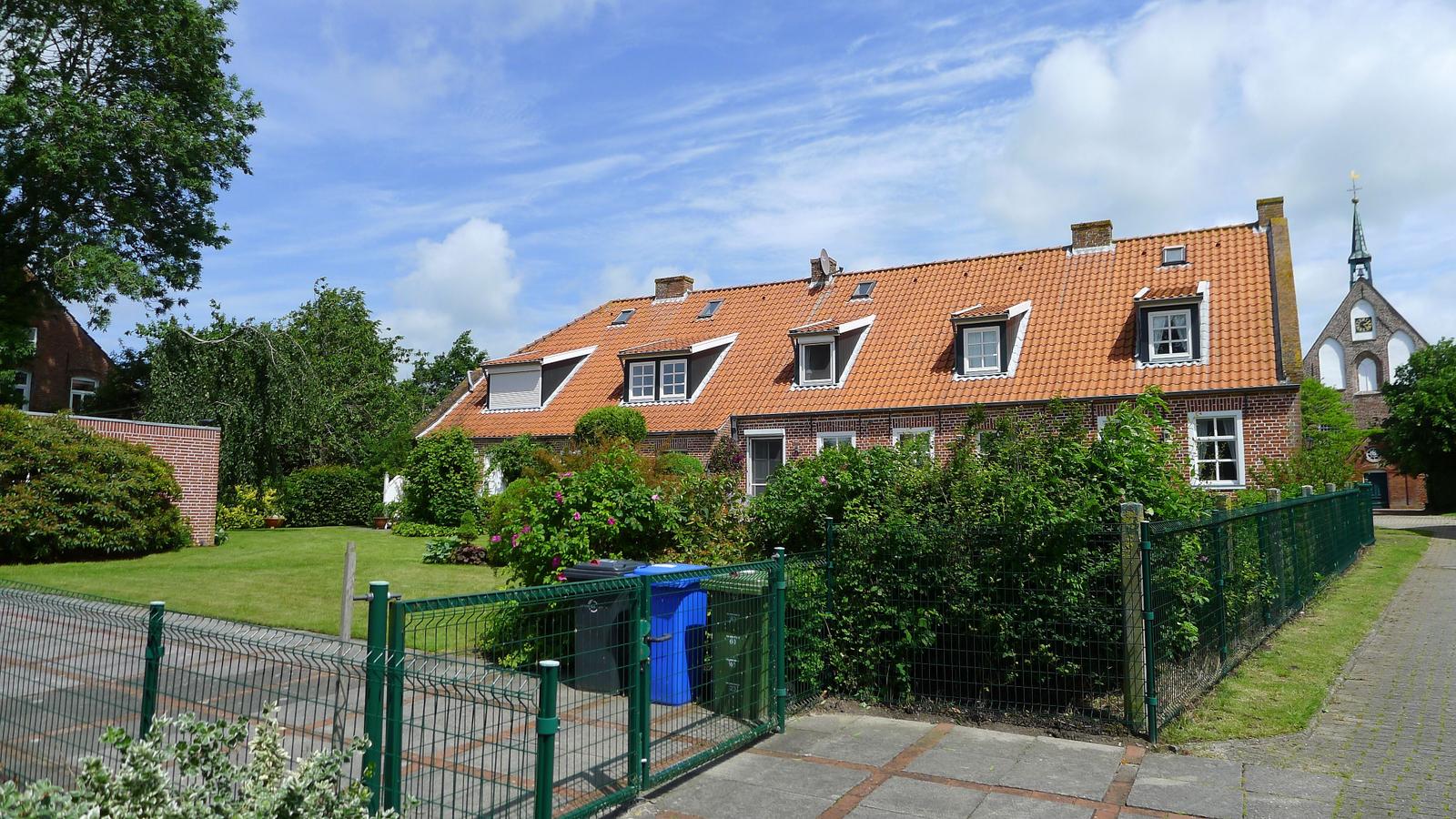 Ein zweigeschossiges Haus mit rotem Ziegeldach und grüner Umgebung.