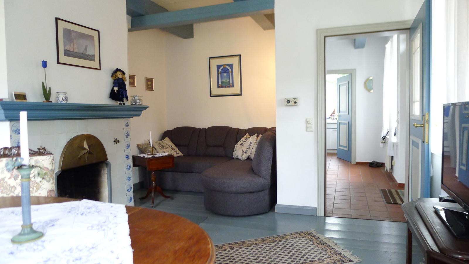 Wohnzimmer mit Sofa, Kamin und Blick in den Flur.