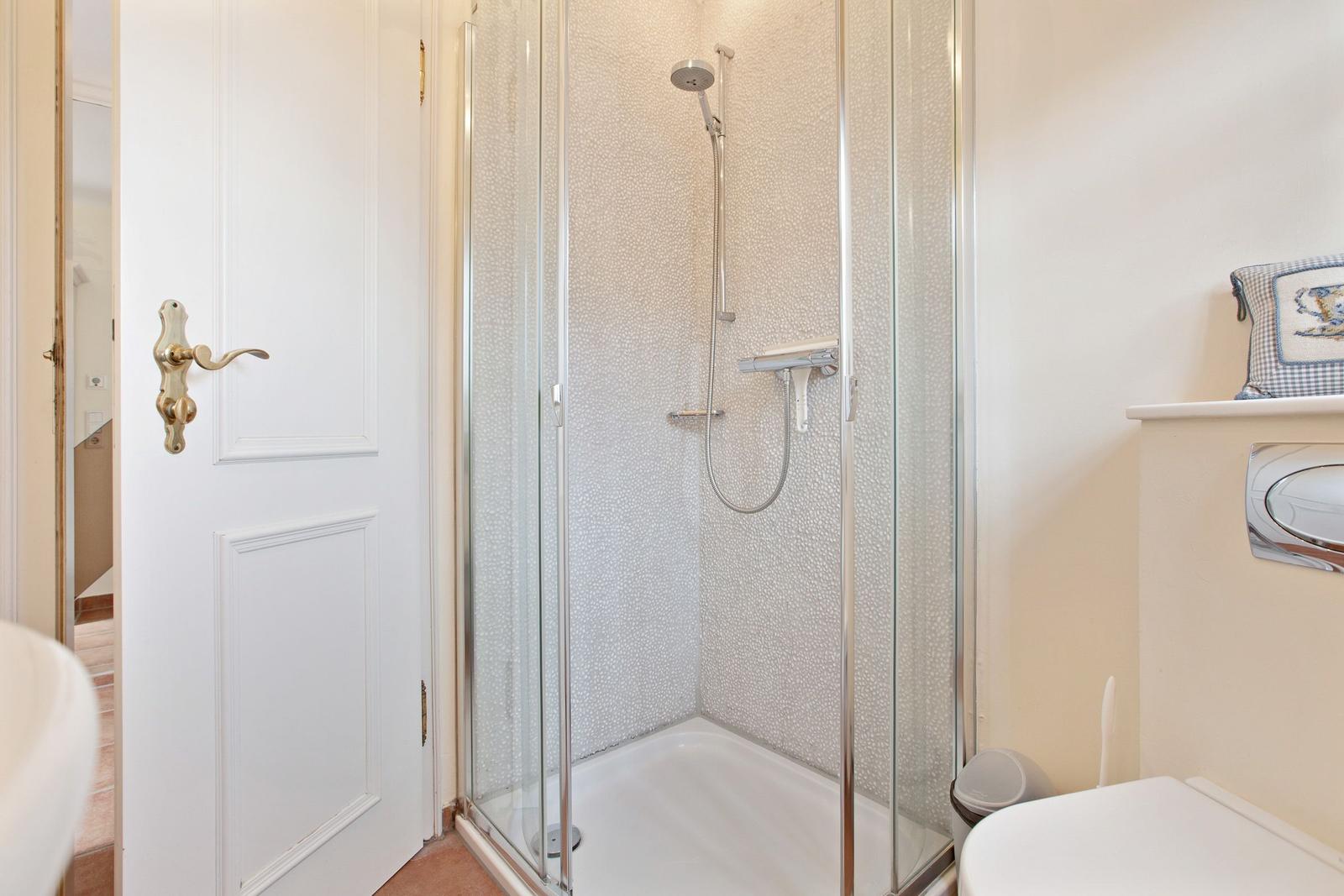 Shower with glass enclosure, toilet, and sink in bathroom