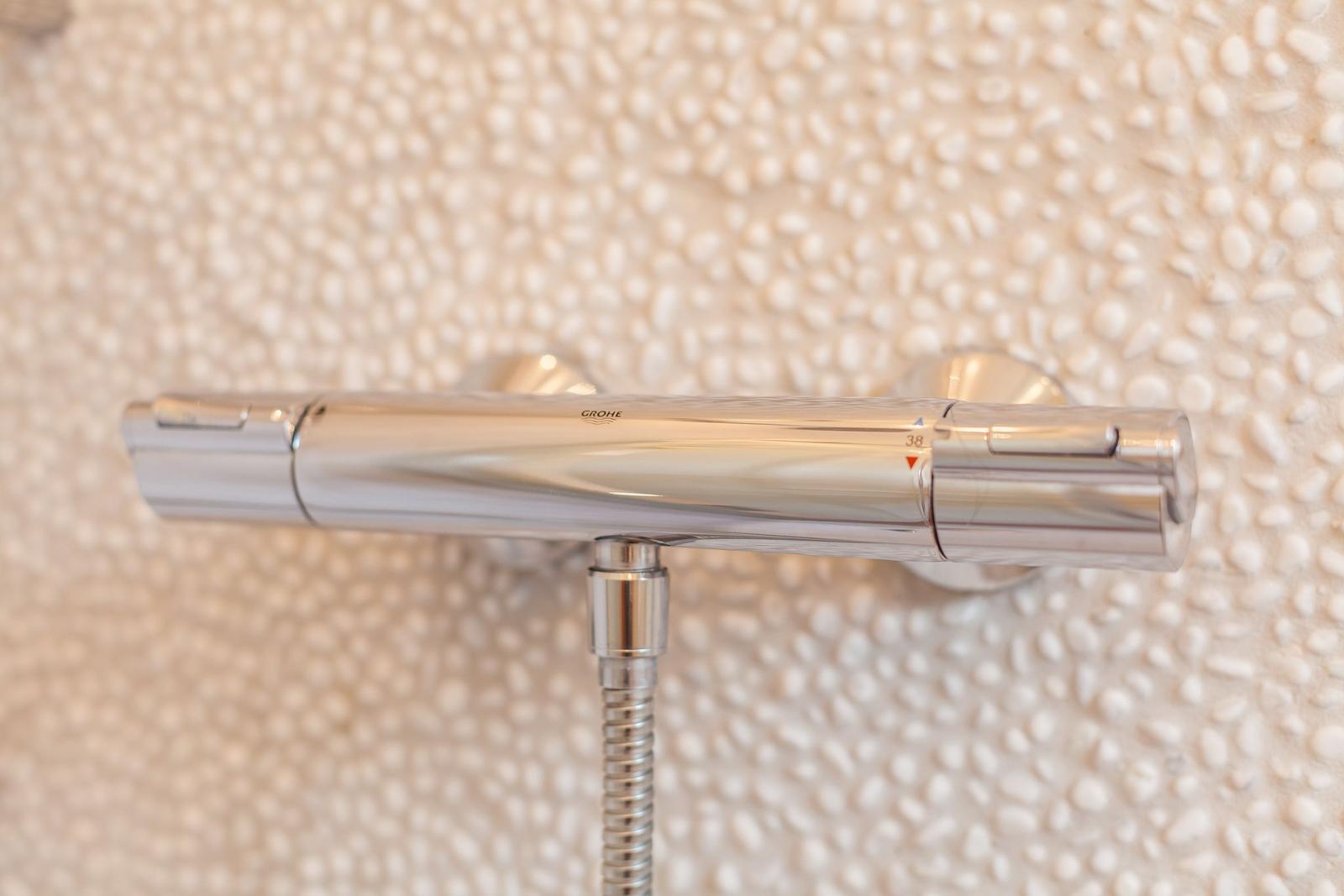 Chrome shower mixer with temperature display on textured wall panel