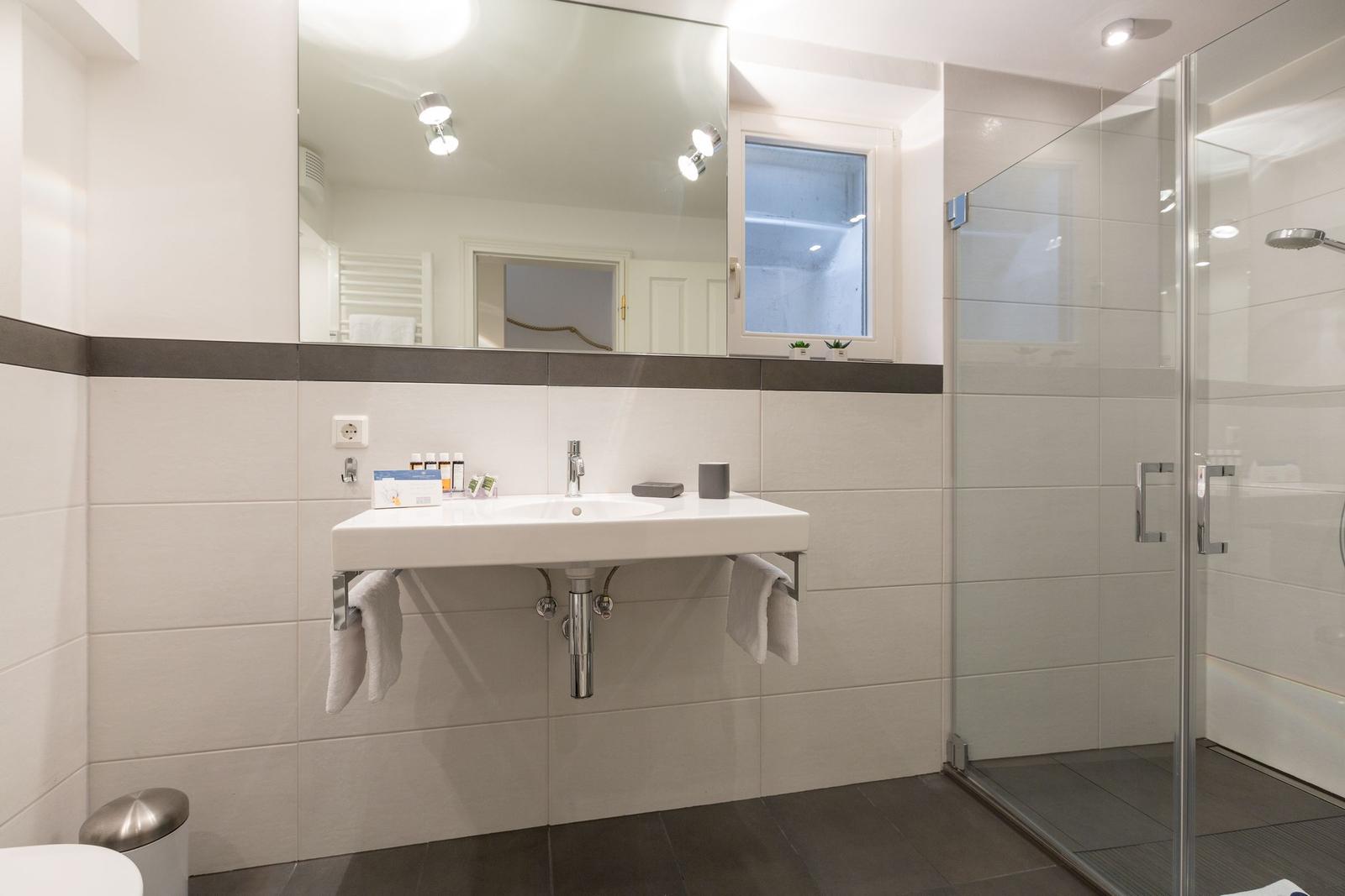 Badezimmer mit Waschbecken, Spiegel und Dusche