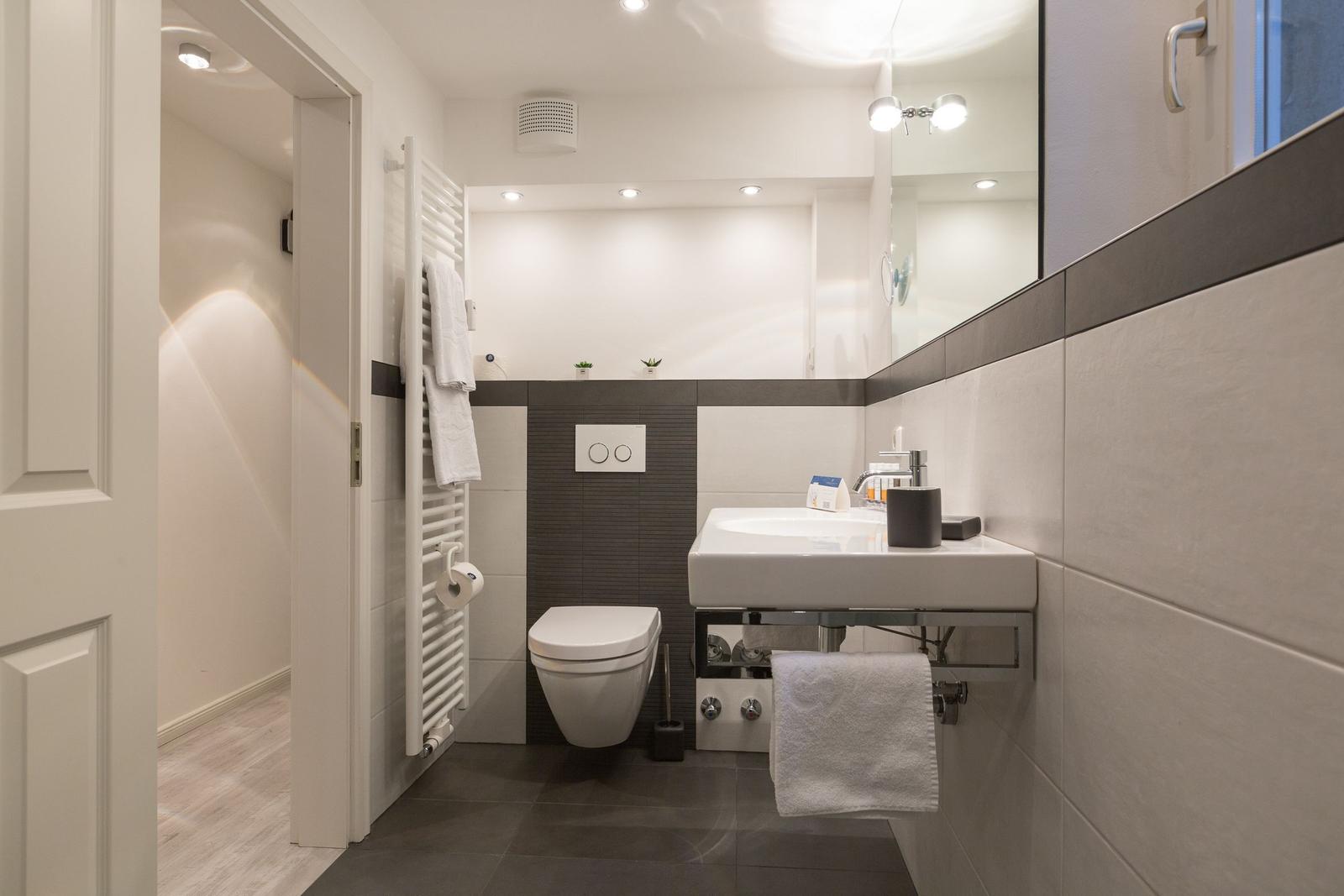 Badezimmer mit Waschbecken, Toilette und Heizung.