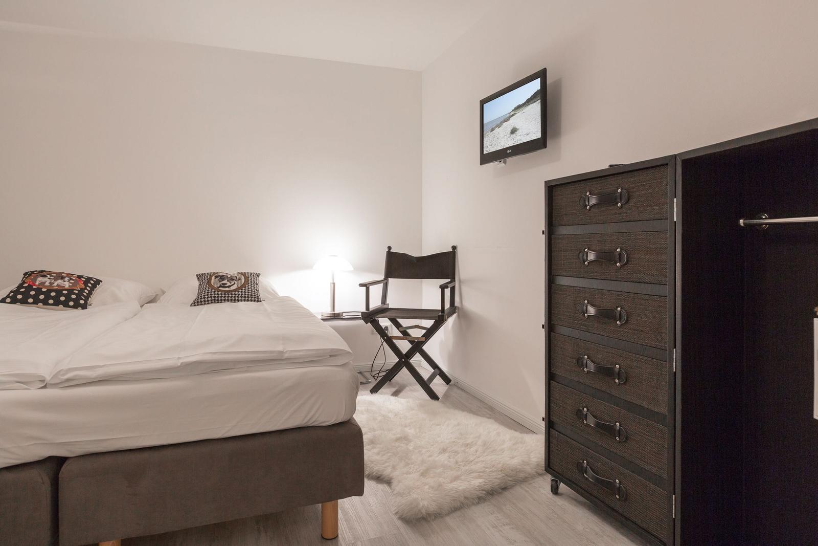 Schlafzimmer mit Bett, Kleiderschrank und Fernseher an der Wand.