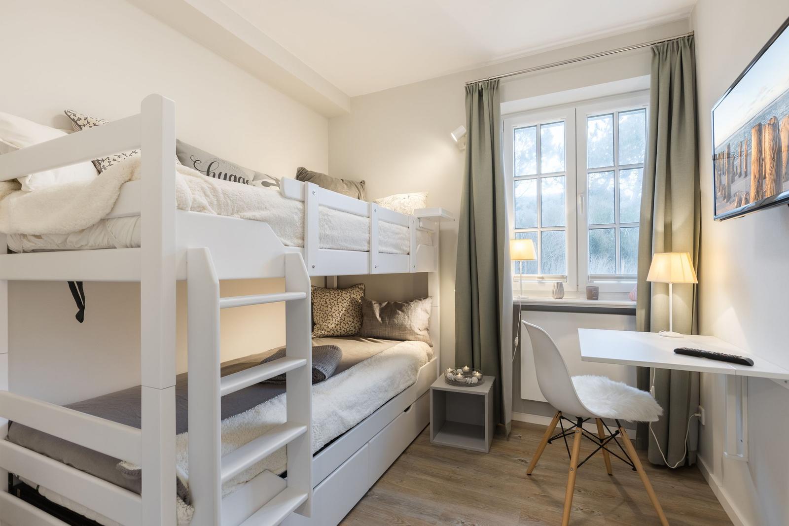Zimmer mit Doppelstockbett, Schreibtisch und Fenster mit Vorhängen.
