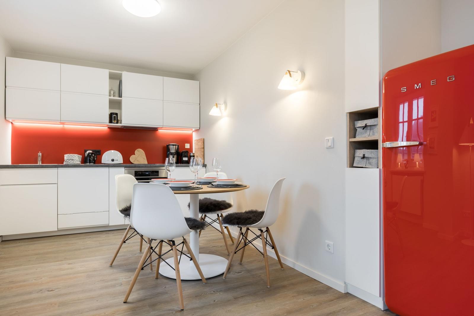 Küche mit Essbereich, roter Kühlschrank und weißen Schränken.