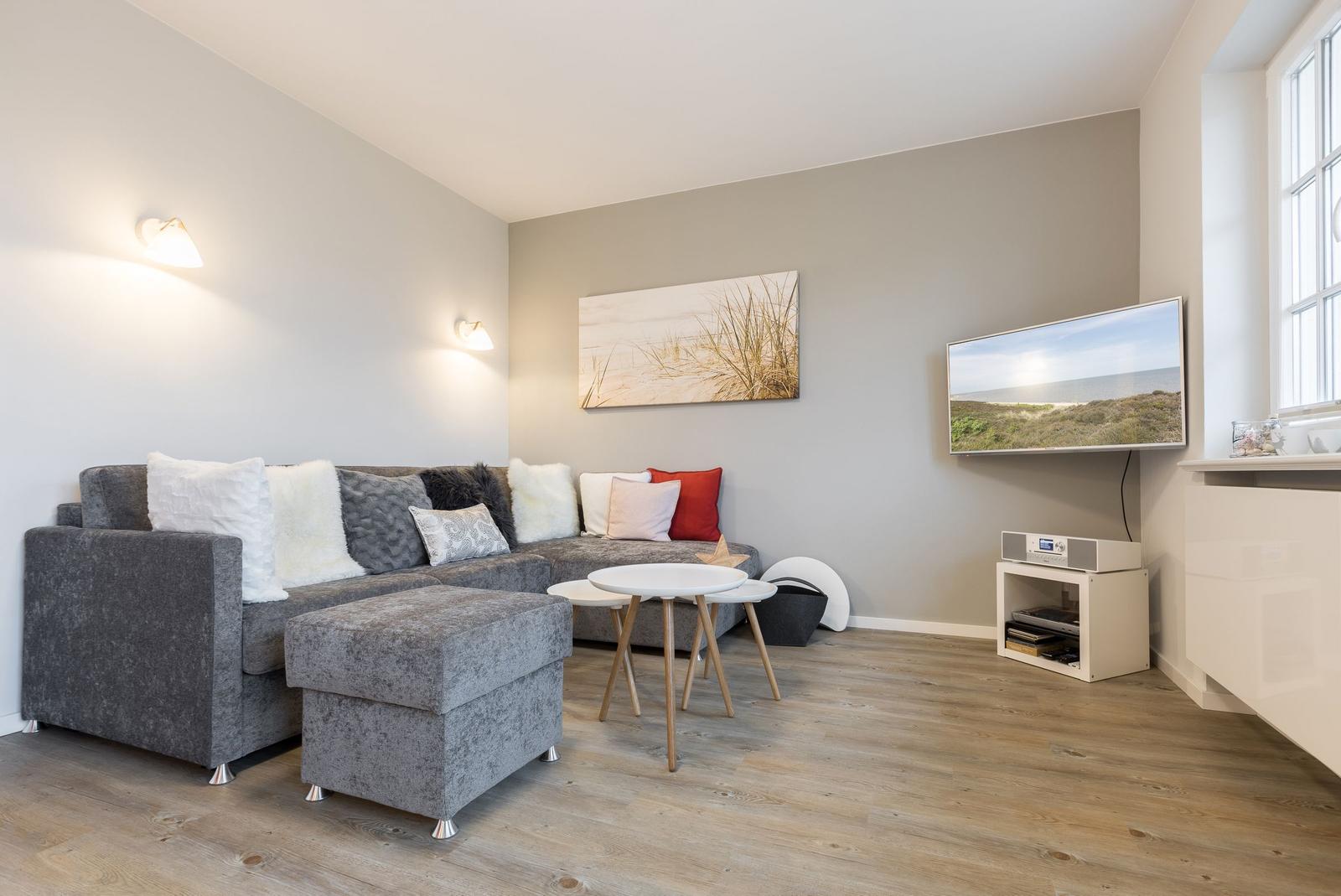 Wohnzimmer mit grauem Sofa, kleinem Tisch und Wandbild