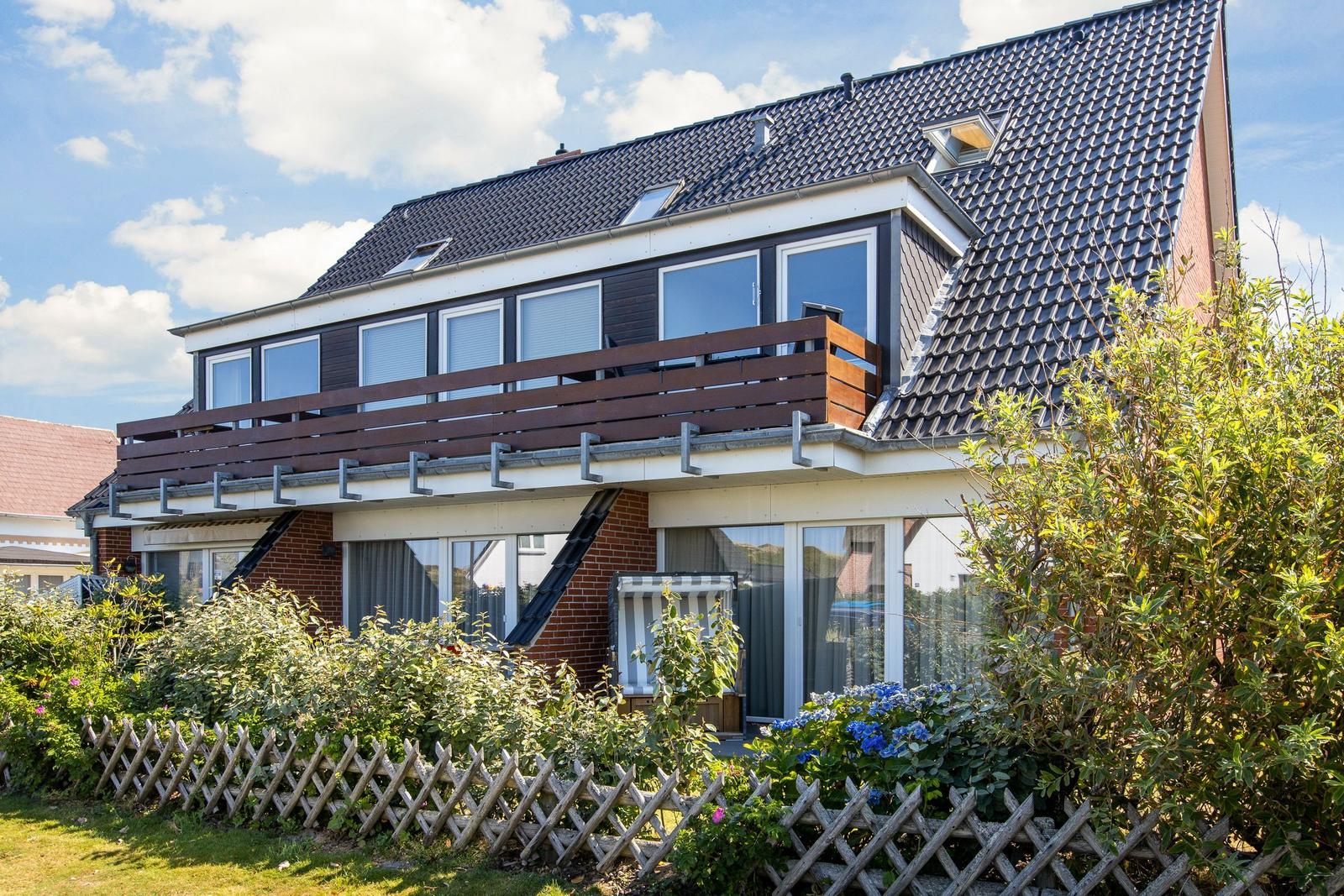 A two-story house with balcony and garden fence.