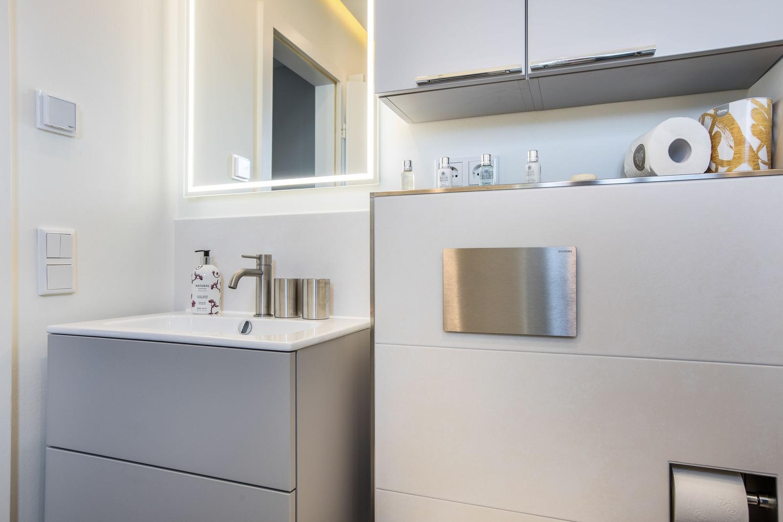 Modern bathroom with sink, mirror, and storage.