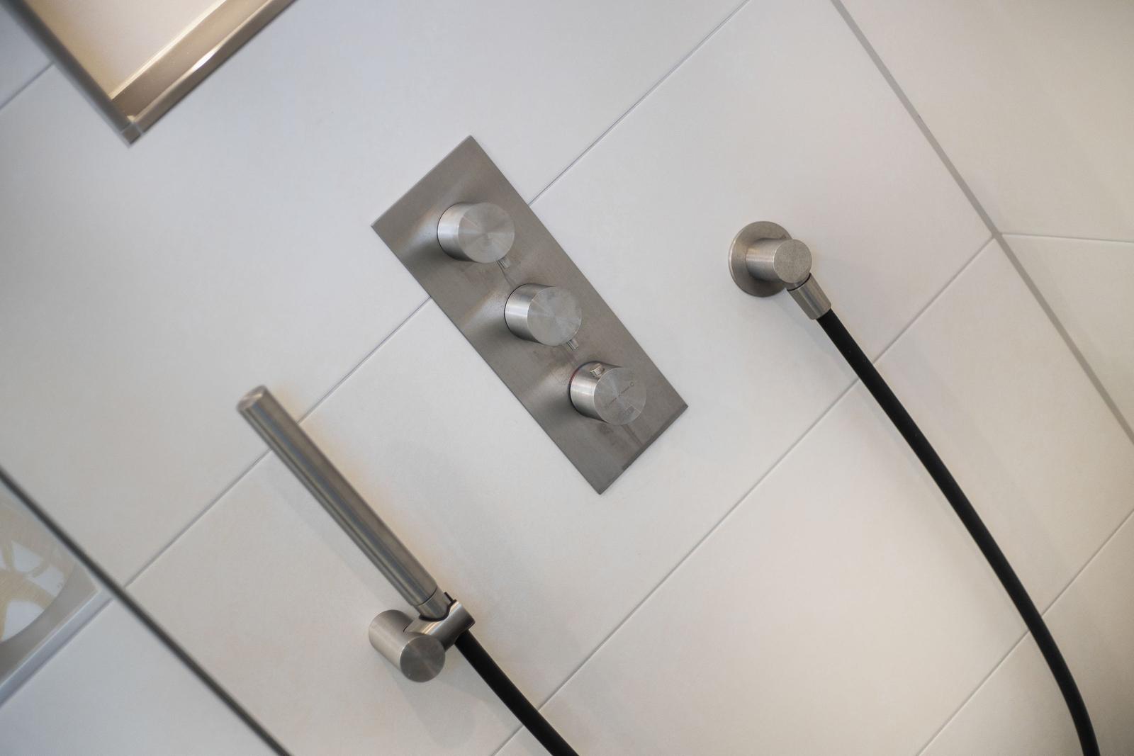 Showerhead with three controls on white wall