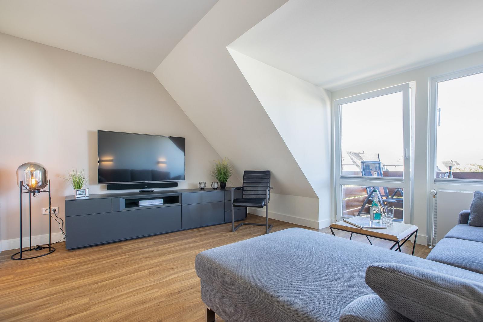 Living room with TV, sofa, and balcony view.