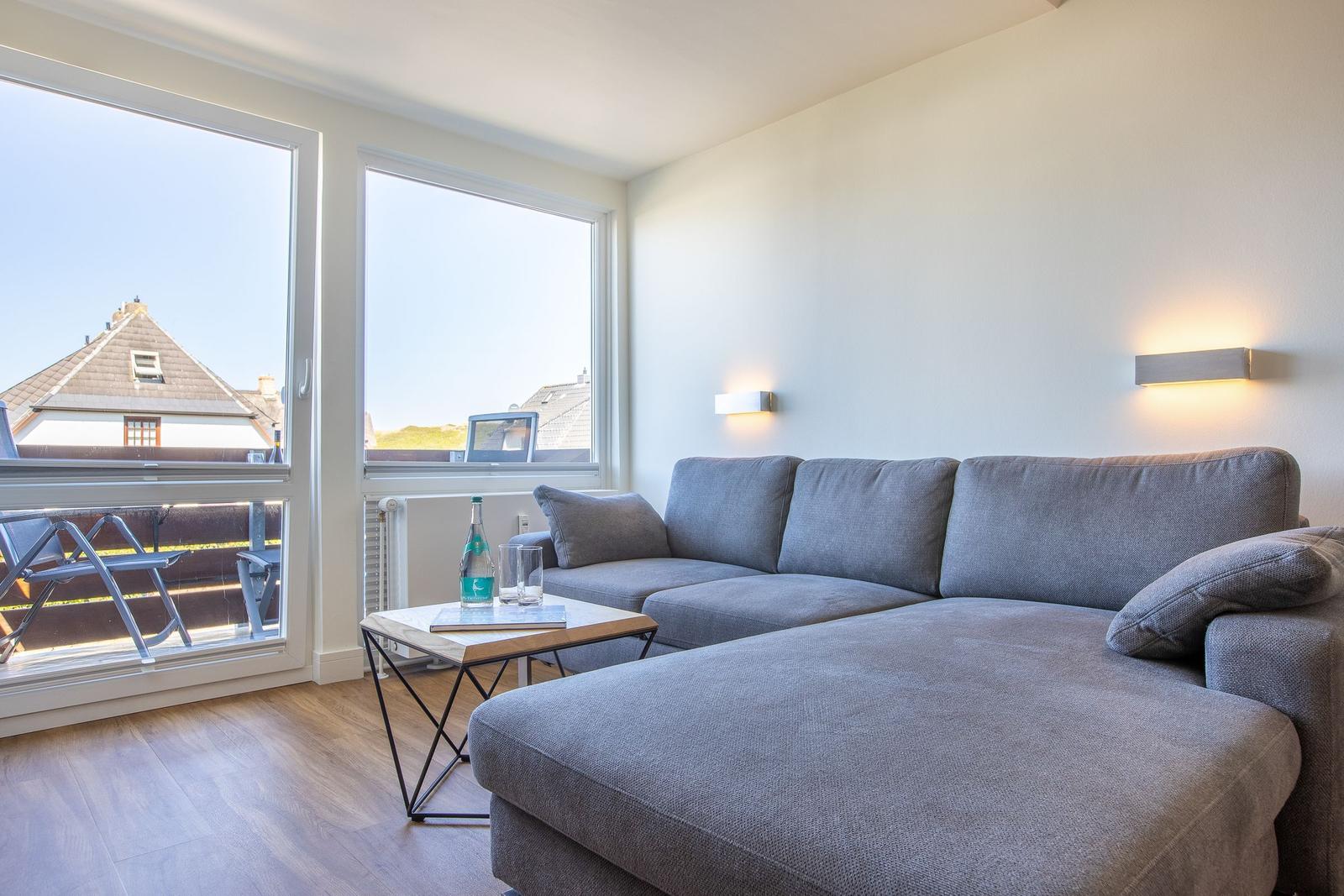 Living room with gray sofa, table, and large windows to balcony.