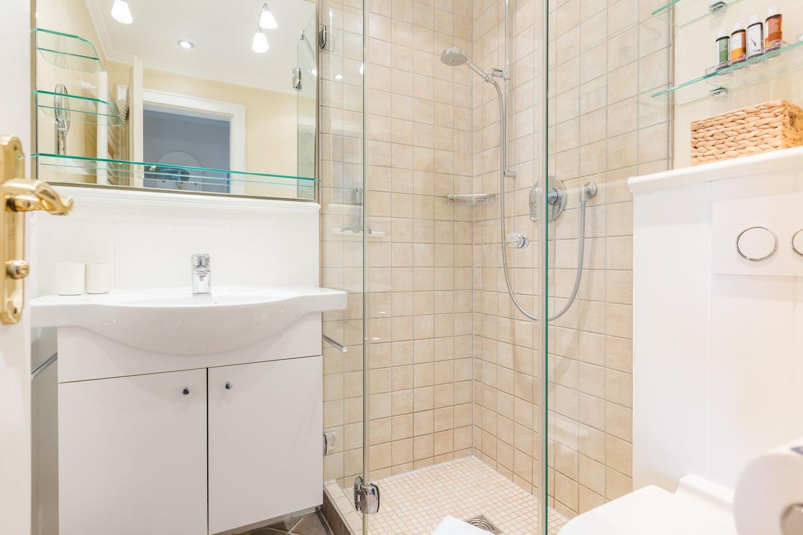 Badezimmer mit Dusche, Waschbecken und Spiegel