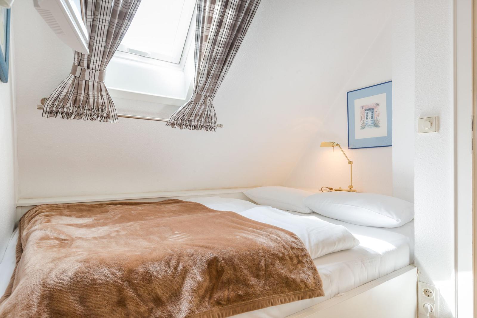 Schlafzimmer mit Dachfenster, Bett und Nachttischlampe.