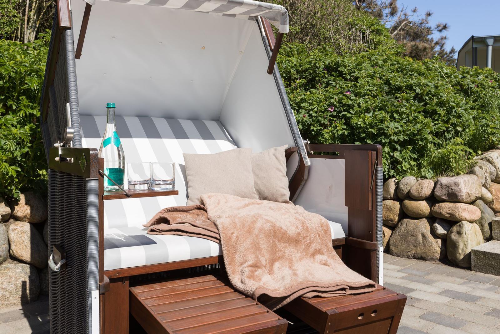 Strandkörbe mit Decke, Kissen und Getränk im Garten.