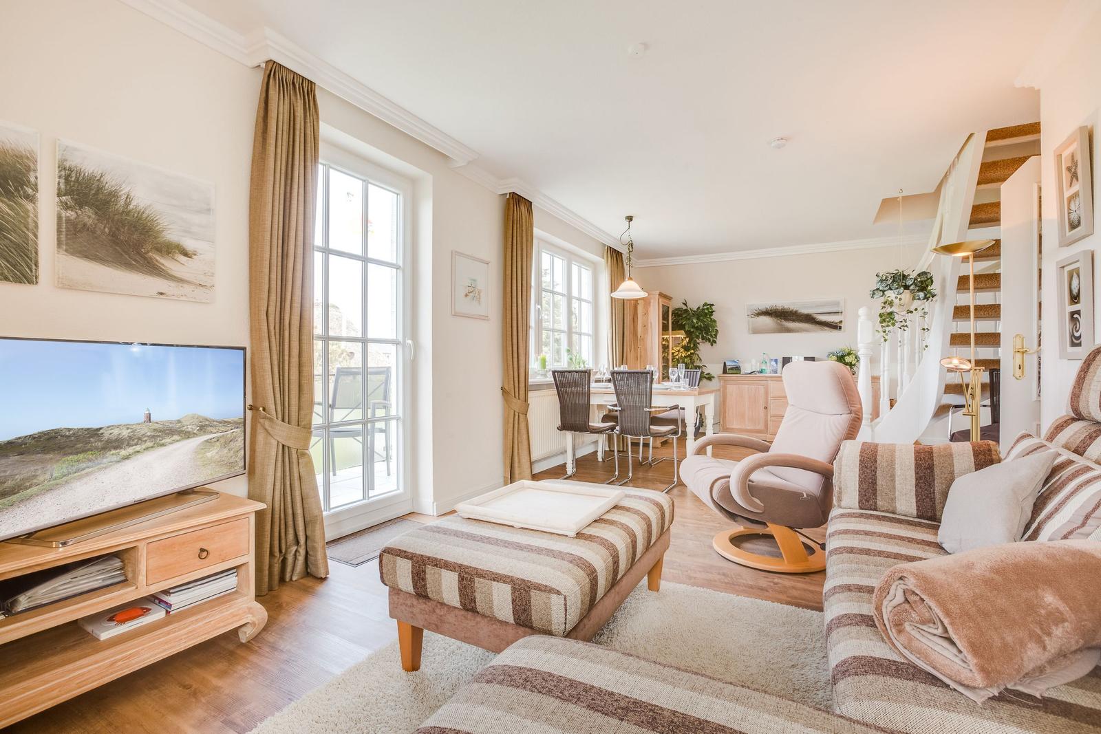 Wohnzimmer mit Sofa, Fernseher und Blick auf Terrasse.