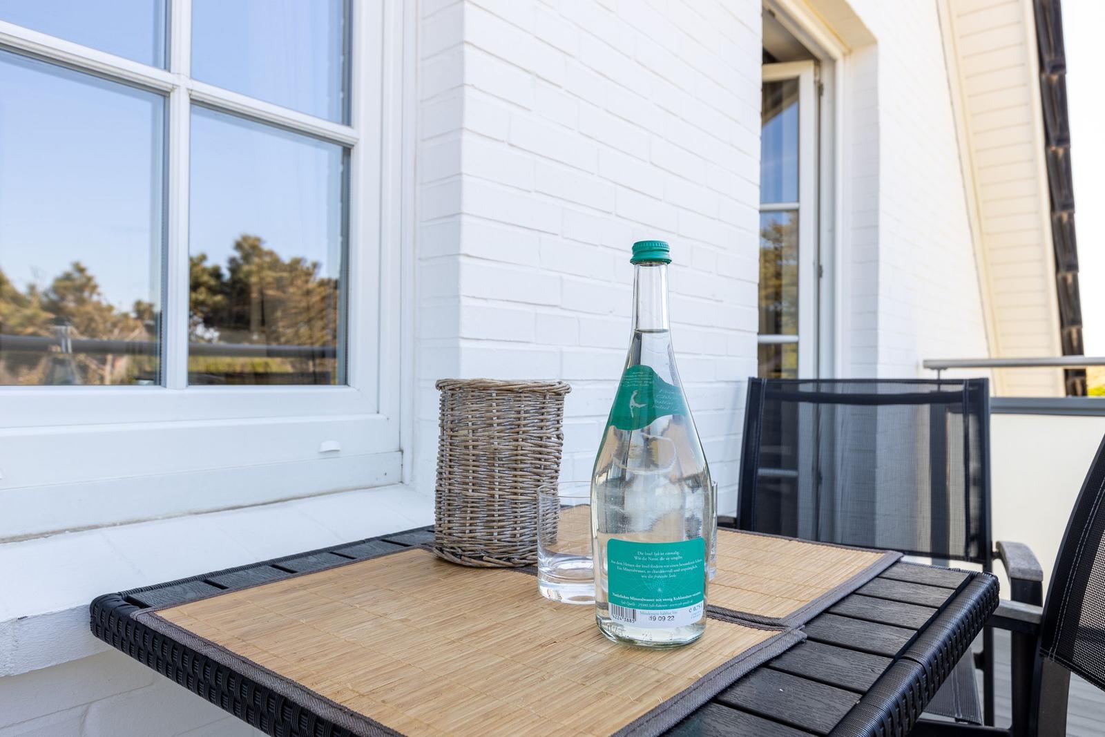 Auf der Terrasse steht ein Tisch mit Wasserflasche und Glas.