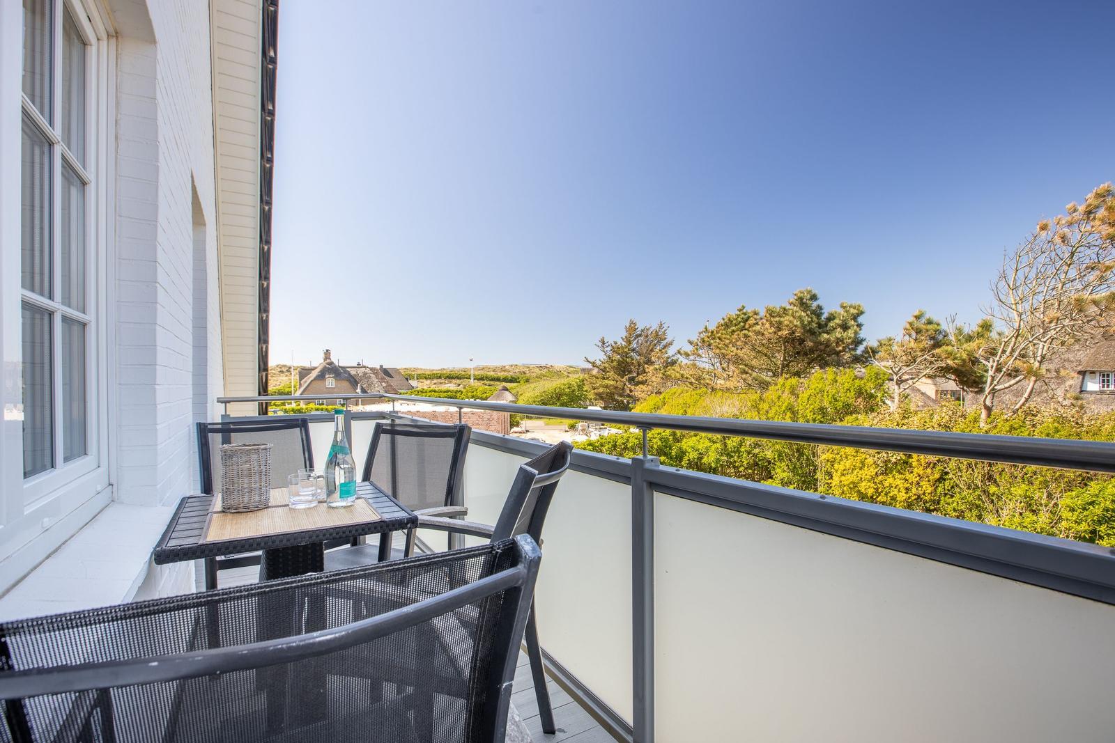 Terrasse mit Tisch und Stühlen, Blick auf Grünflächen und Häuser.