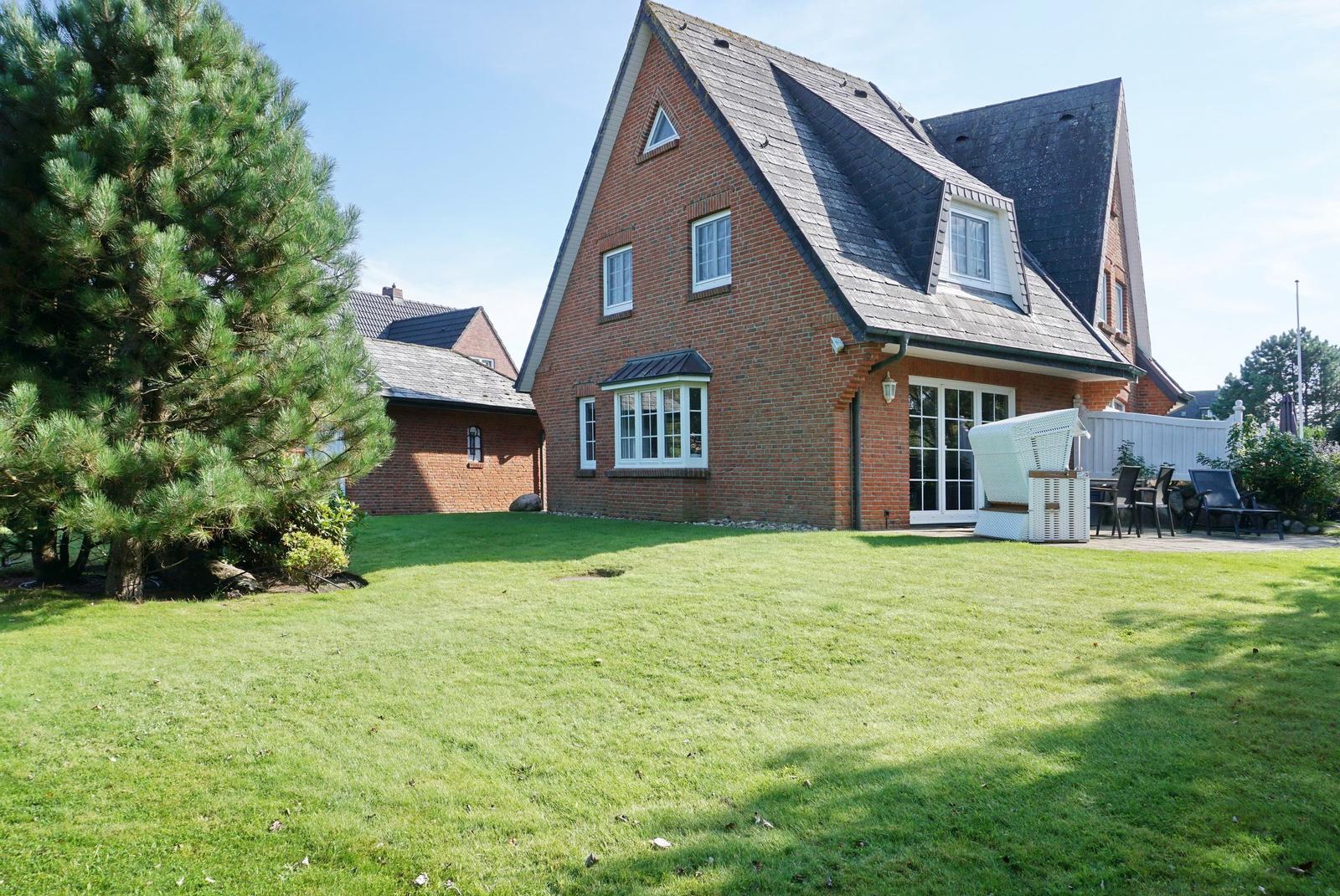 Red brick house with large garden and terrace with garden furniture.