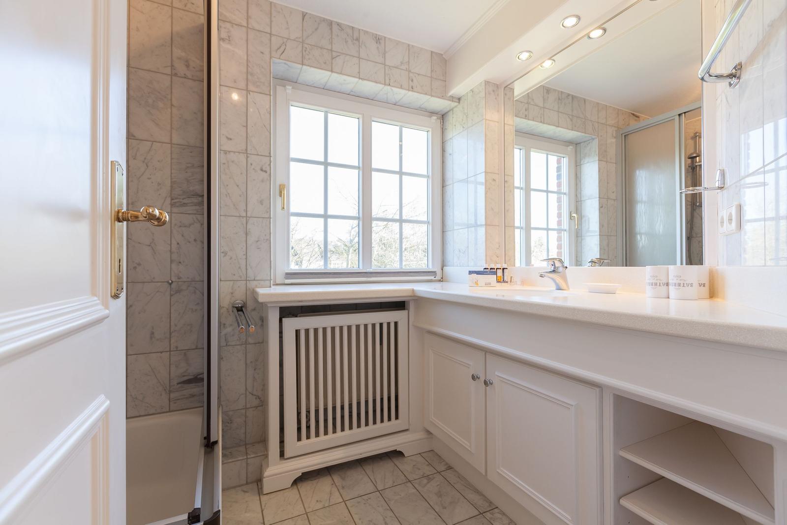 Bathroom with shower tub, window, and sink with mirror.