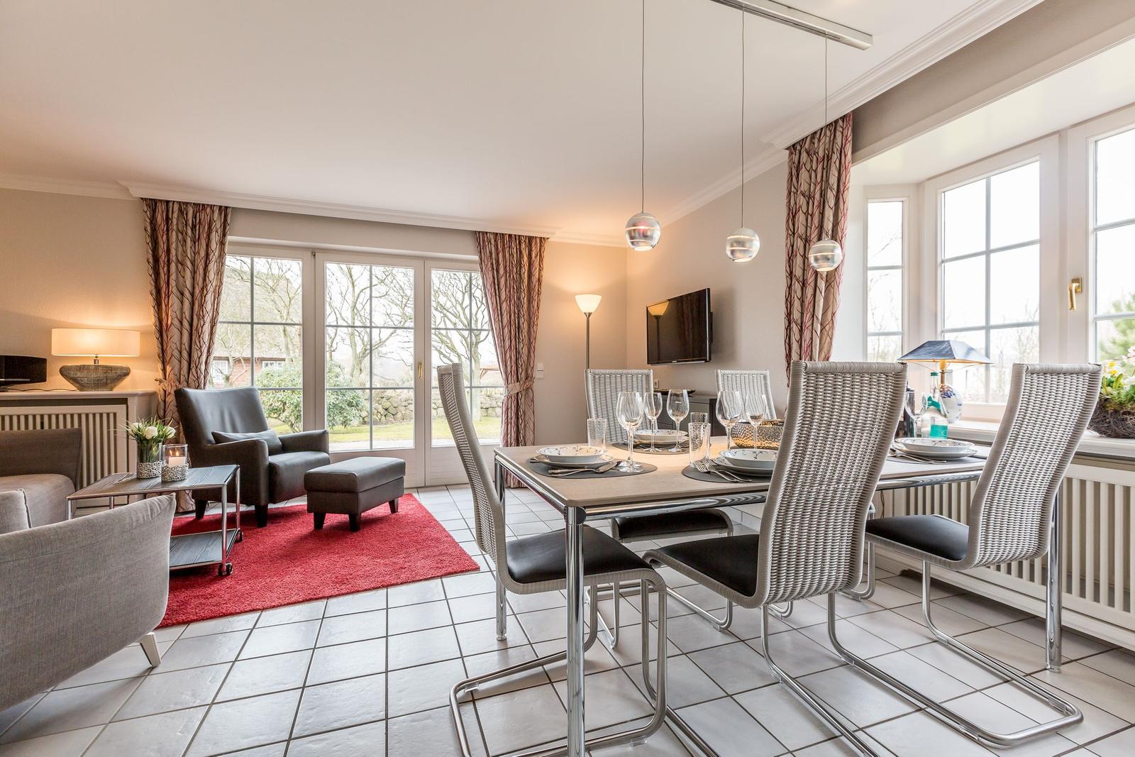 Dining area with six chairs and dining table. Living area with seating and red rug.