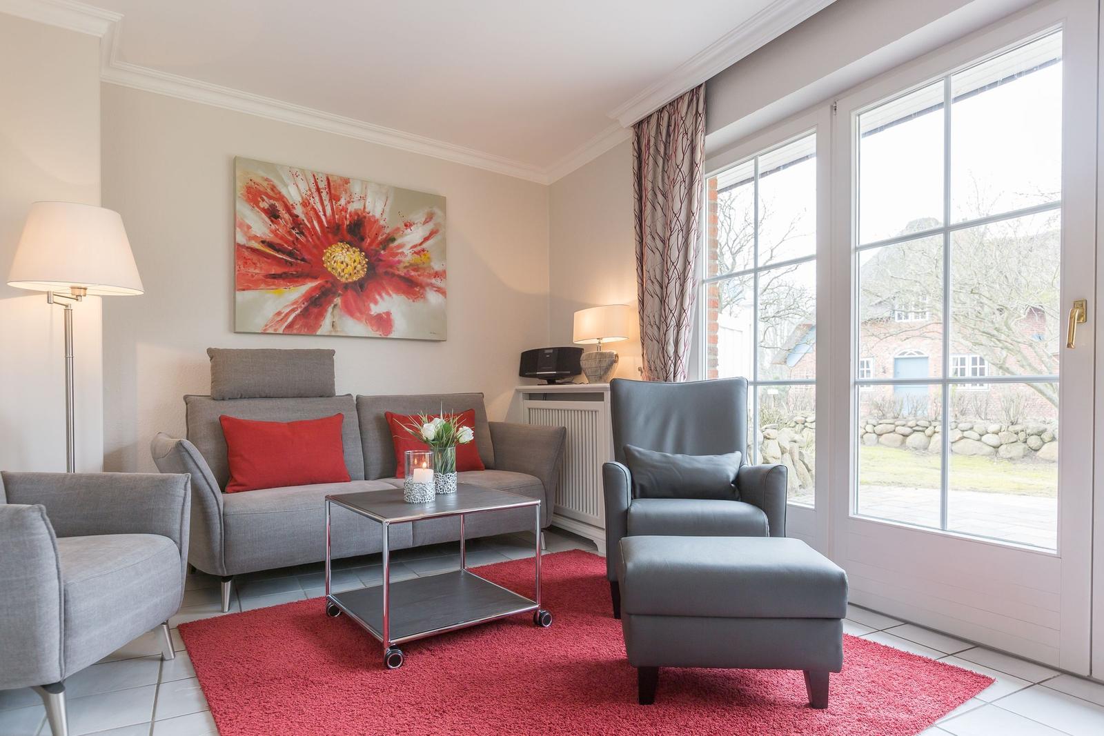 Living room with gray sofa, red rug, and large window.