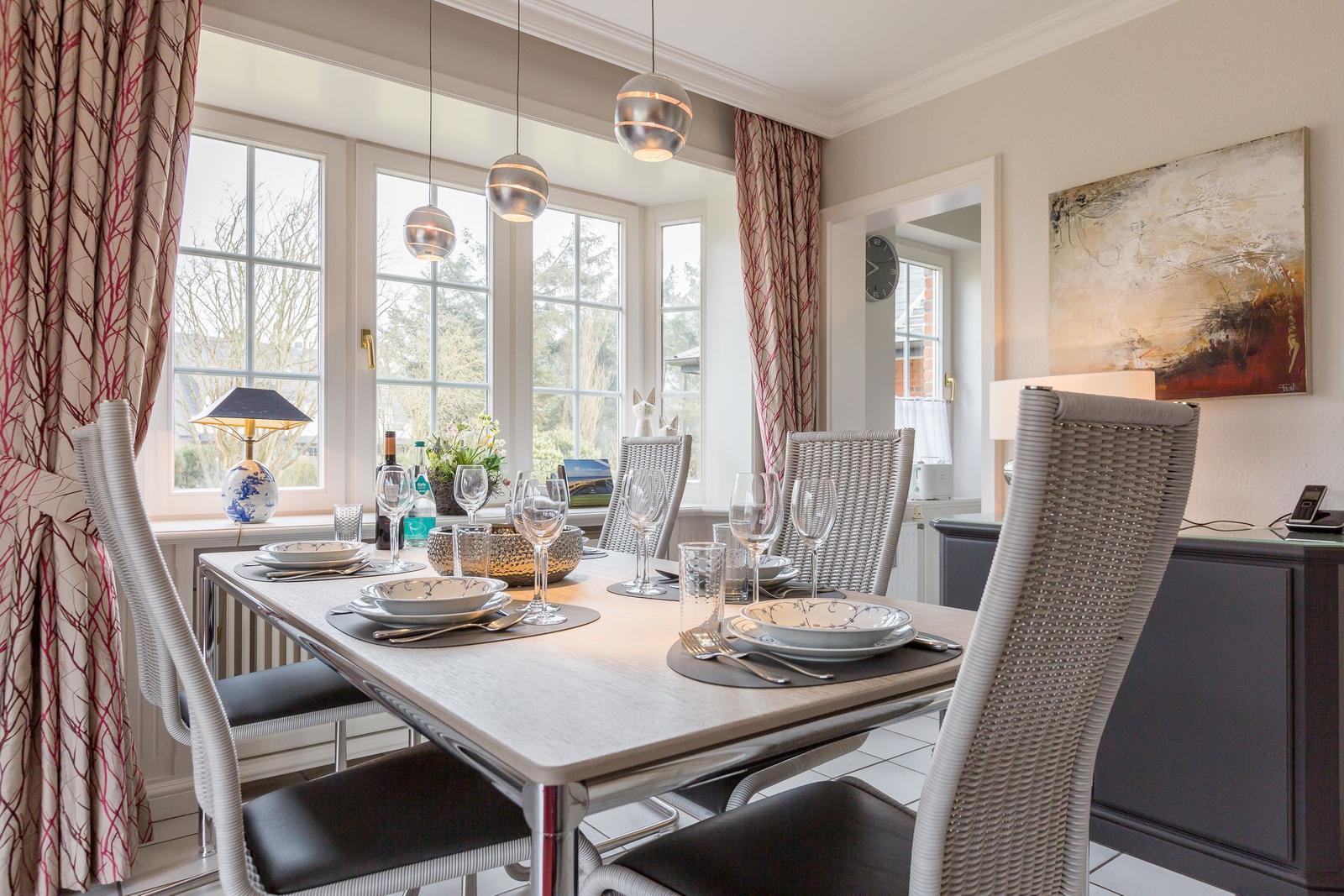 Dining table with chairs, windows, and wall art in dining room.