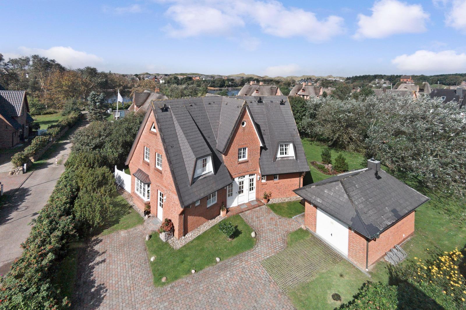 Red brick house with gray roof and paved courtyard.