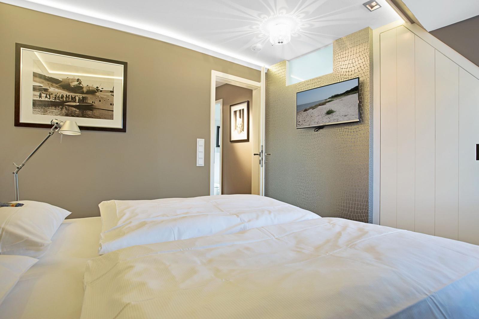 Schlafzimmer mit Bett, Wandbild und Fernseher an der Wand