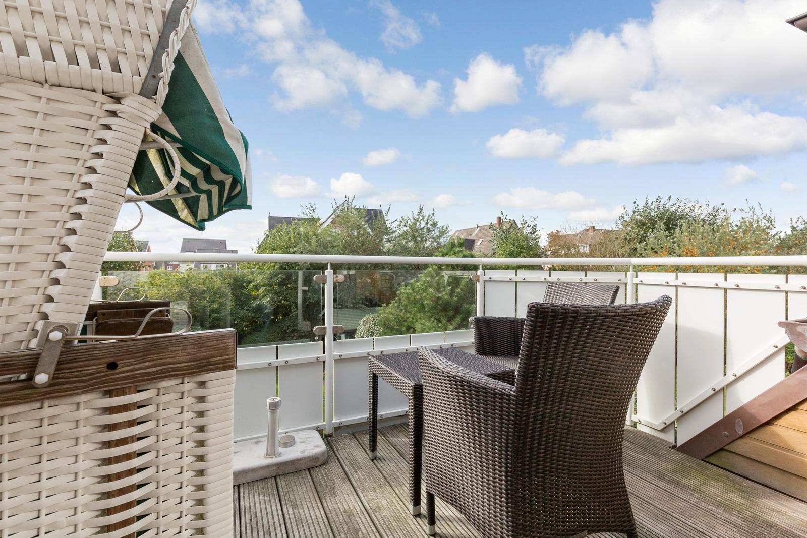 Terrace with wicker furniture and view of green areas and houses