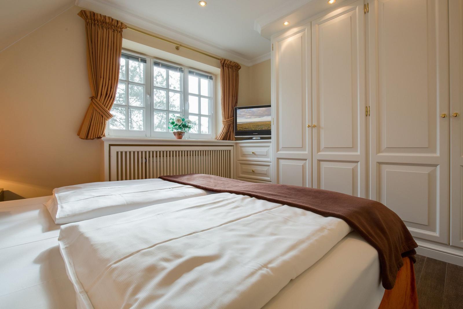 Bedroom with bed, window, and wardrobe.
