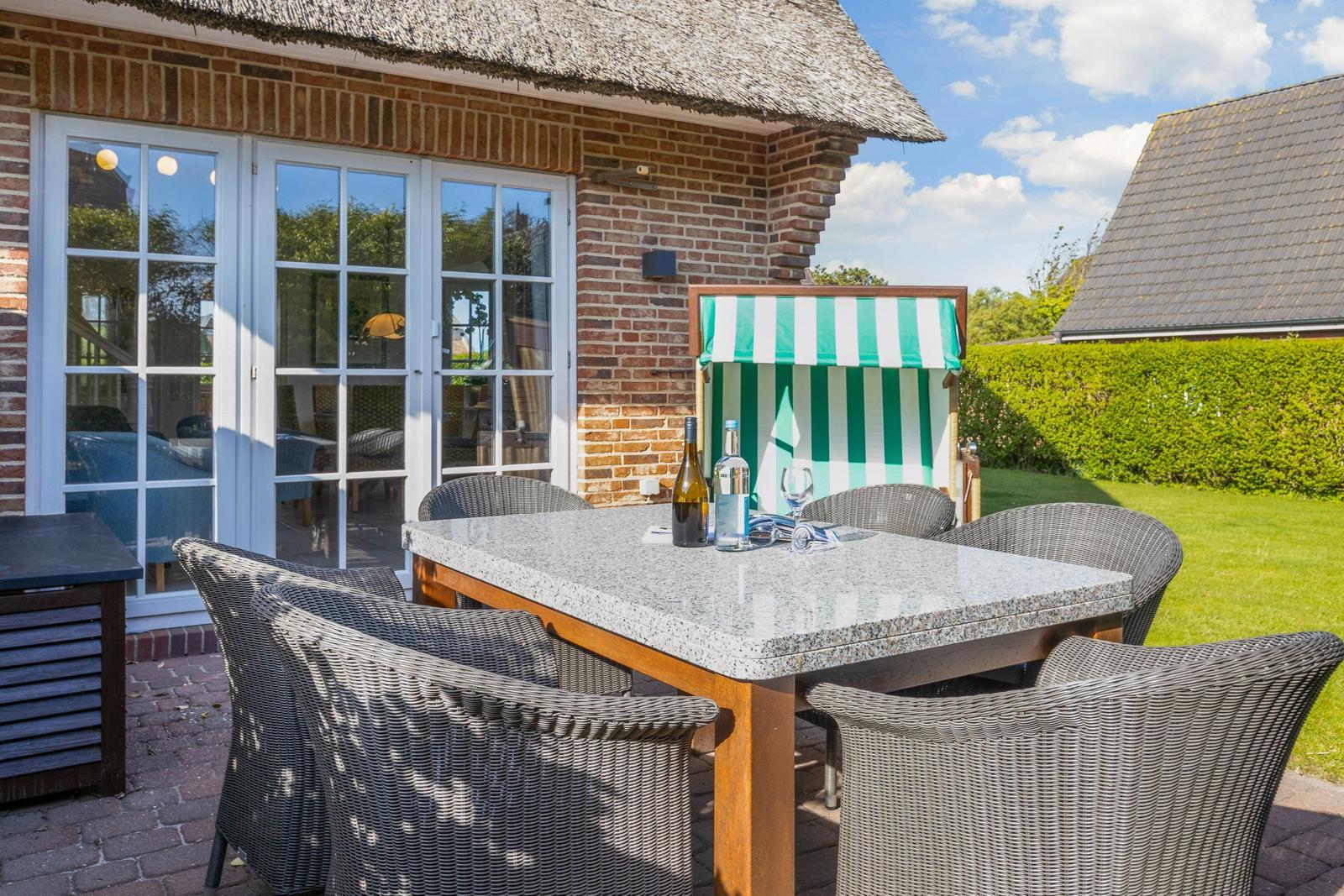 Terrace with dining table, chairs, and green-white awning.