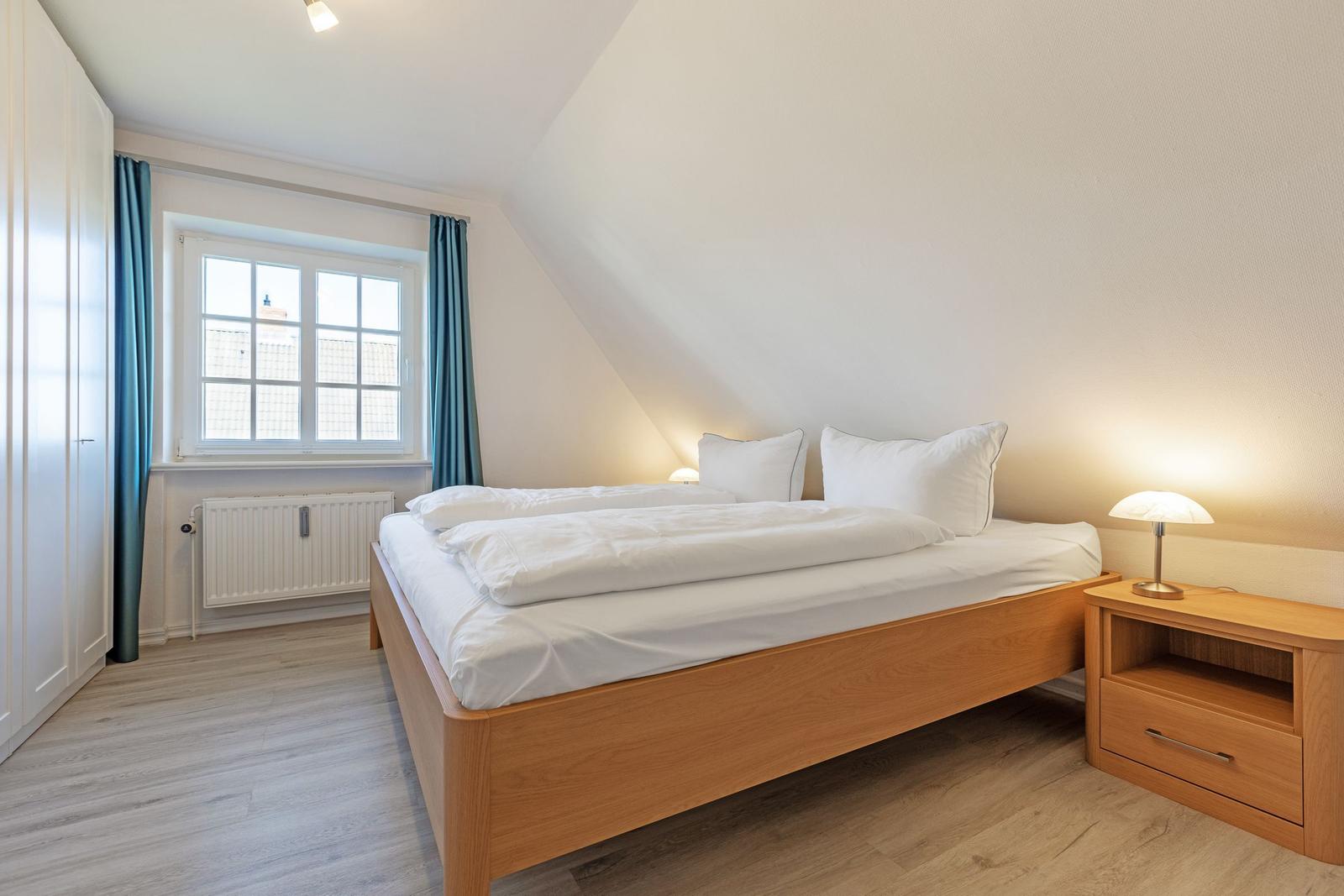 Bedroom with double bed, nightstand, and window with curtains.