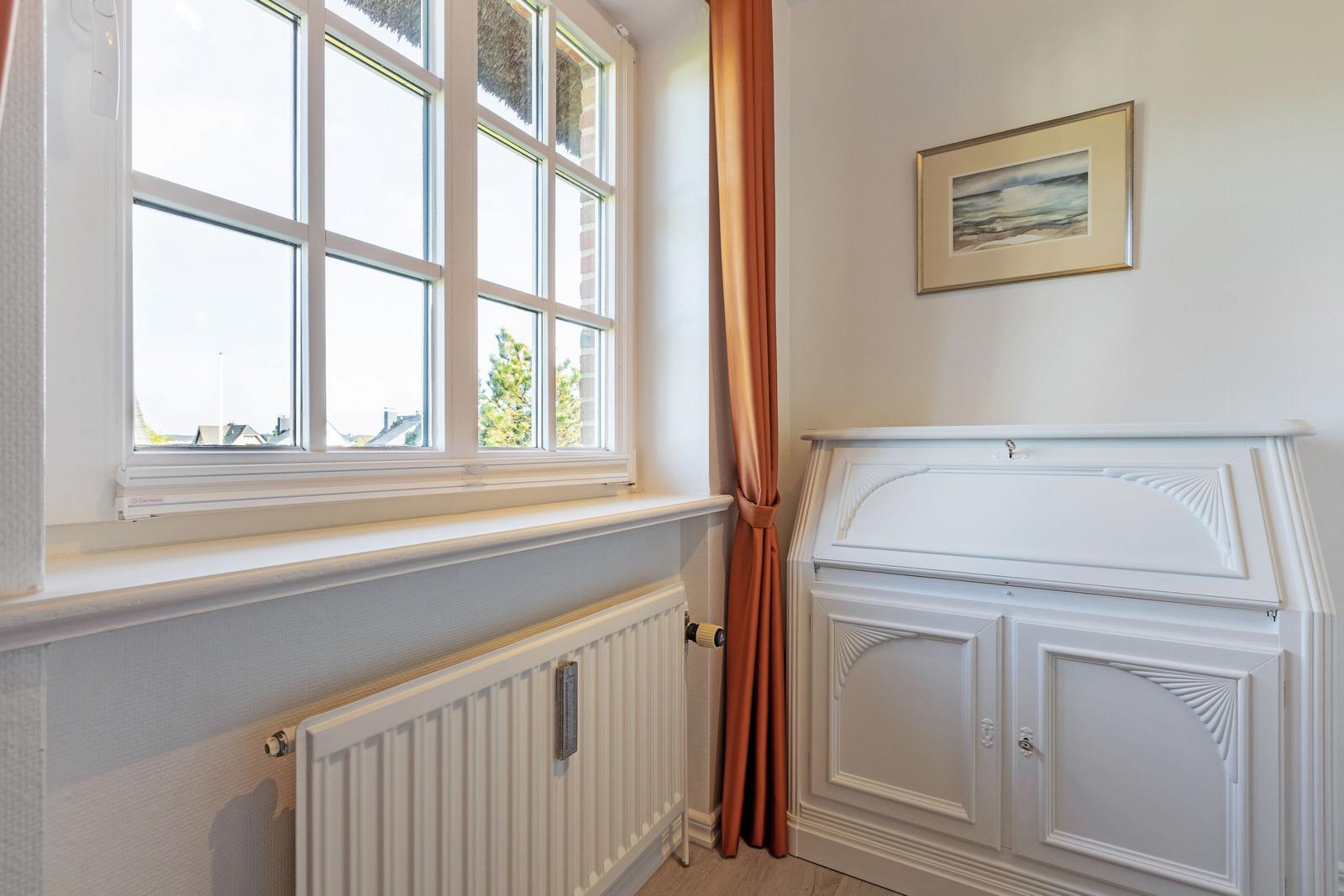Room with window, radiator, and white cabinets.
