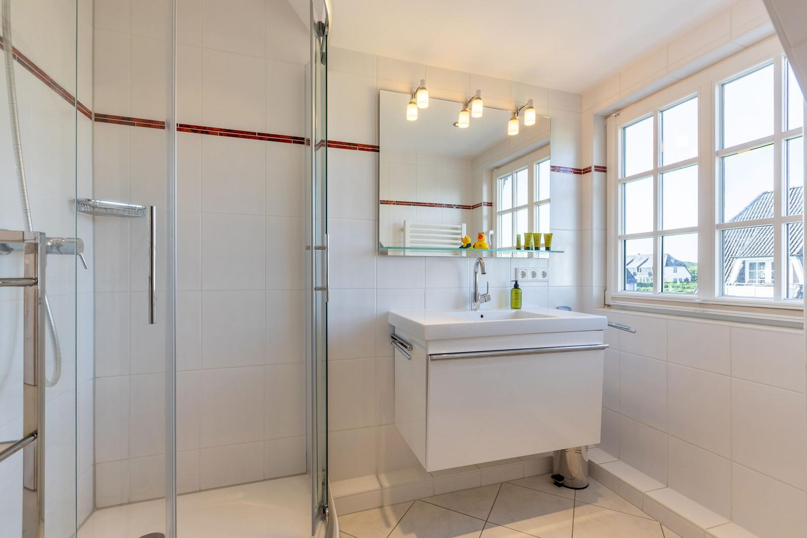 Bathroom with shower, sink, and window