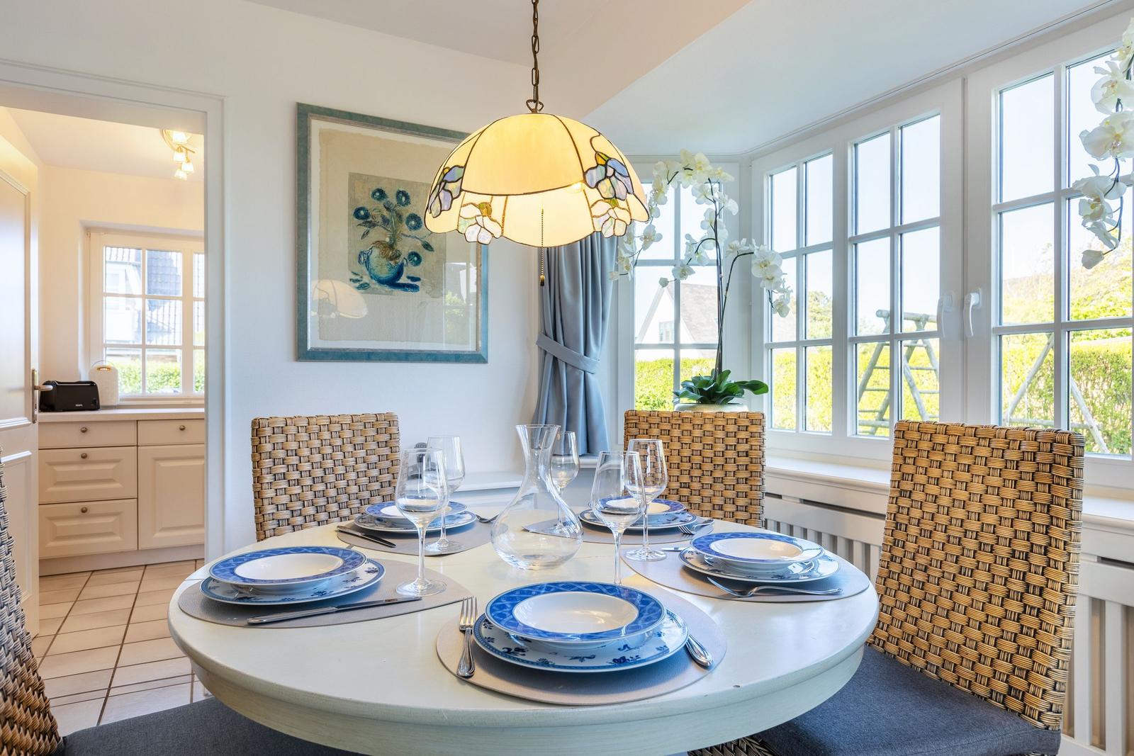 Round table with chairs, floral decor, and window view.