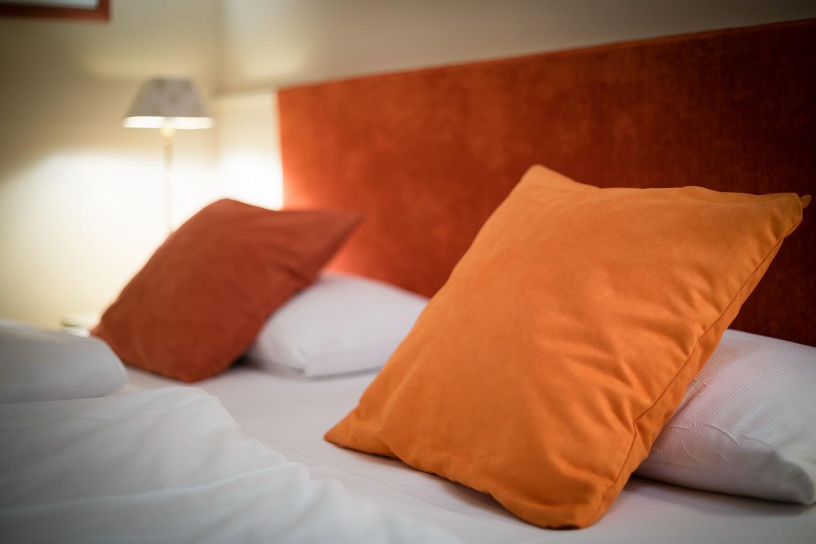 Bed headboard in orange with pillows on bed