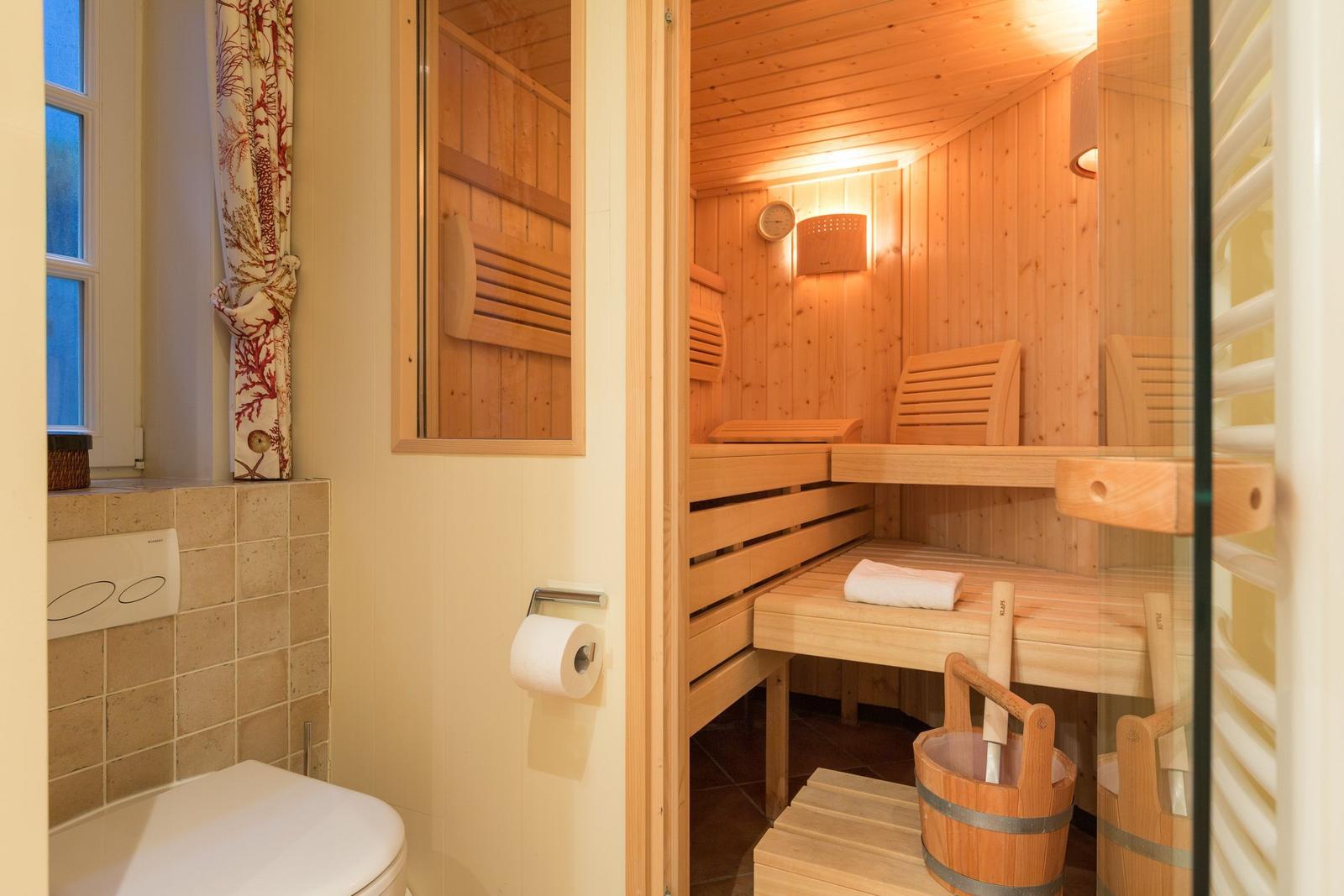 Sauna with wooden benches and entrance area with toilet and window