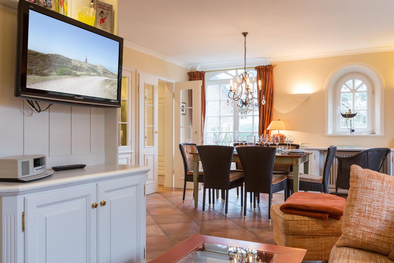 Living and dining area with TV, table, chairs, and windows.